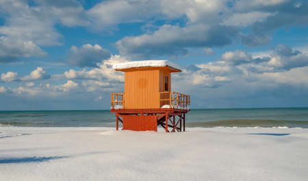 An orange lifeguard tower on a snowy beach in winterの写真素材