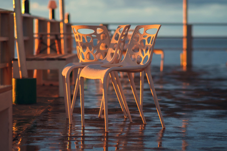 Wet chairs illuminated by the sunset raysの写真素材