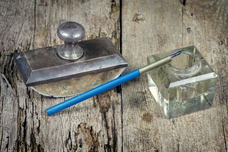 Old vintage presse papier and inkpot with ink pen on a grunge wooden tableの写真素材