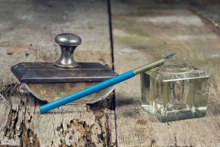 Old vintage presse papier and inkpot with ink pen on a grunge wooden tableの写真素材