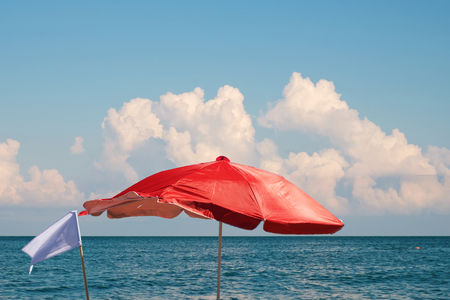 red beach umbrella and white flag on the sea sideの写真素材