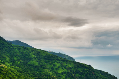 Green hills with sea and cloudy sky backgroundの写真素材