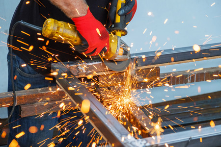 men working with hand grinder on metal construction