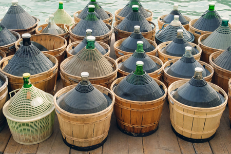Large Glass Wine Bottles on the wooden surface with sea background