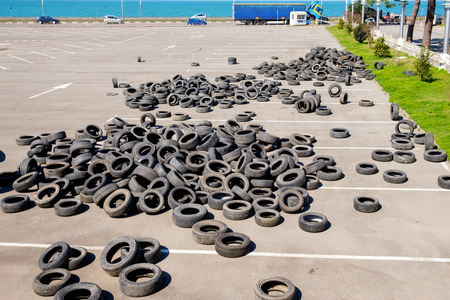 Pile of old car tires on the asphalt, blue sea backgroundの写真素材