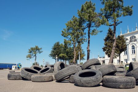Pile of old car tires on the asphalt, trees and blue skyの写真素材