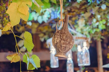 Decorative bottle hang from ceiling covered by grapes, selective focus