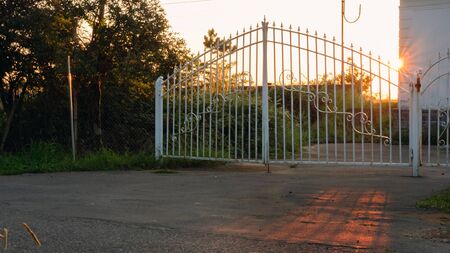 Sun rays through the rusty metal white gate 