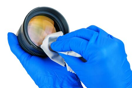 hands cleaning digital camera lens from dust with white cleaning cloth, isolatedの写真素材