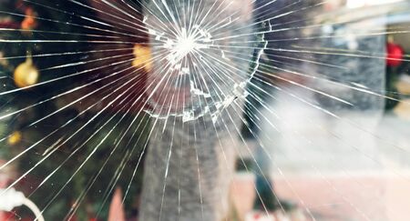 Cracked glass on the a shop's window reflecting a view of the street