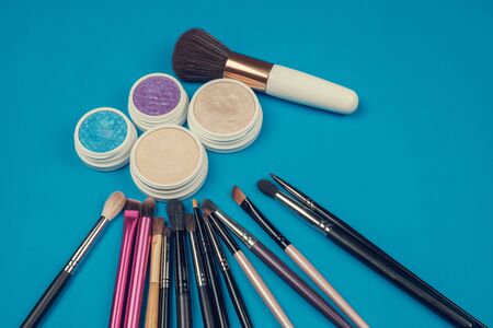 Makeup cosmetics products, brushes and  accessories on a blue surface の写真素材