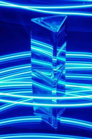 Glass Prism with reflection on a abstract blue neon stripey background