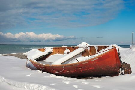 Red fishing boats on the snow covered beachの写真素材