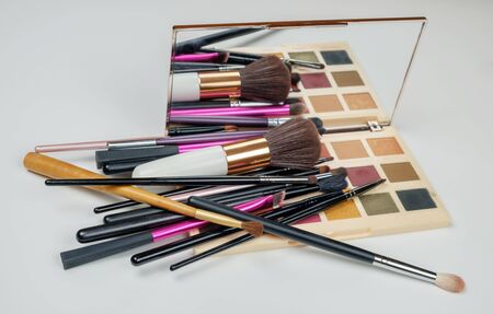 Makeup cosmetics products, brushes and palette on a white surface 