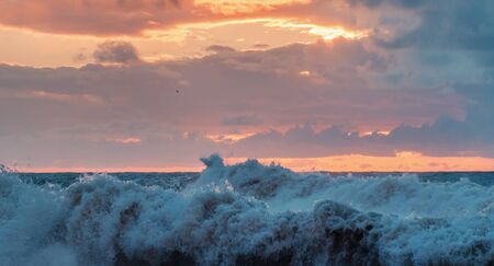 Crashing waves and colorful cloudy sunset sky の写真素材