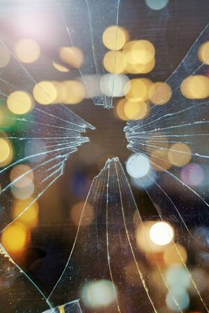 Blurred abstract city lights background behind the dirty broken glass