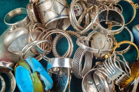 A collection of different rings and jewelry on a dark green velvet background, top view