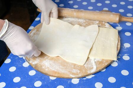 Hands of a chef preparing dough on the wooden cutting board 