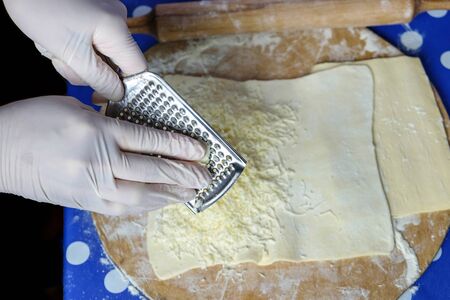 Hands of a chef grating cheese on the flat dough
