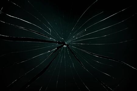 Broken and cracked glass with hole on a black background