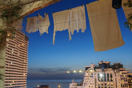 A white laundry hanging to dry in the balcony with night dark blue sky background の写真素材