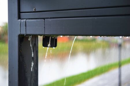 Blurred natural rainy background with water drops in motion. Heavy rain pouring from the roof,...