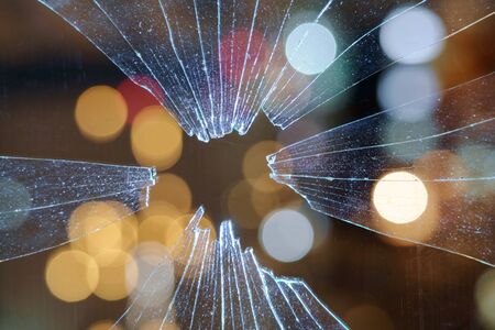 Blurred abstract city lights background behind the dirty broken glass