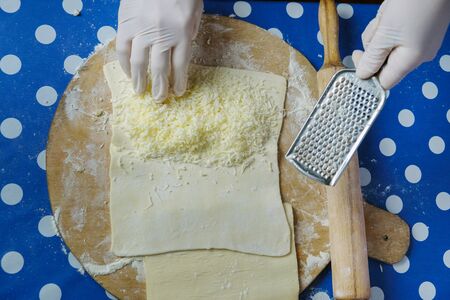 Hands of a chef grating cheese on the flat dough 