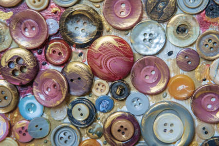 Different color buttons for clothes on a painted surface. Close-up