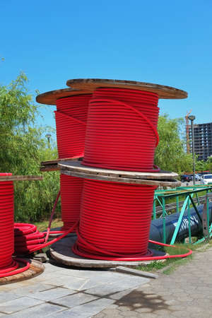 Wooden coils with red power cables in the park
