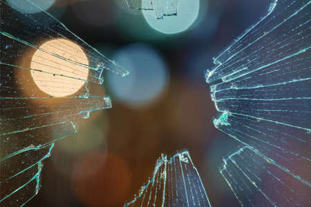 Blurred abstract city lights background behind the dirty broken glass