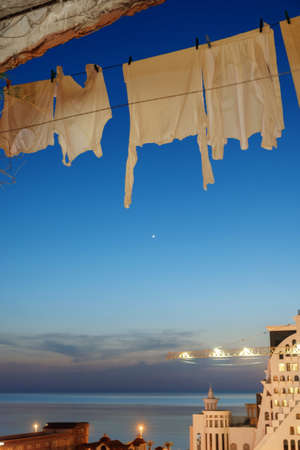 A white laundry hanging to dry in the balcony with night dark blue sky backgroundの写真素材