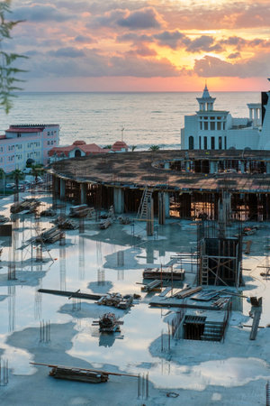 Puddles reflecting sky on the empty construction site with sea and beautiful sunset sky backgroundのeditorial素材