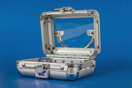 A small transparent glass and metal open suitcase on a blue background.