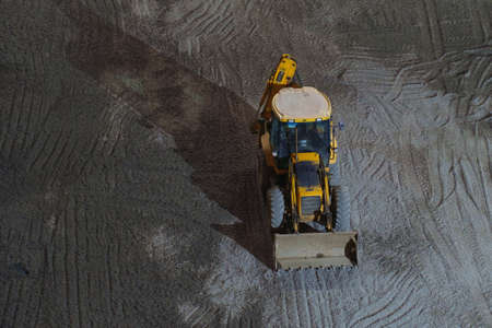 Yellow tractor with drop shadow during a night on the gravel ground