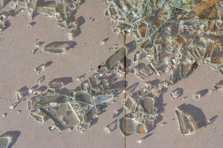 Small pieces of broken glass on the ground illuminated by the sunlight, top view