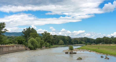 Blue cloudy sky over the forest and flowing river