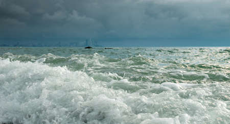 White foamy waves at the sea with blurred cityscape backgroundの写真素材