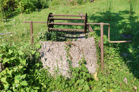 An old abandoned well in a field overgrown with green ivy