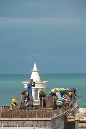 Batumi, Georgia, September 22, 2020: Building worker working on the top of the construction site, blue sea and sky backgroundのeditorial素材