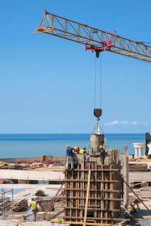 Building worker pouring concrete on the top of the construction site with blue sea backgroundの写真素材