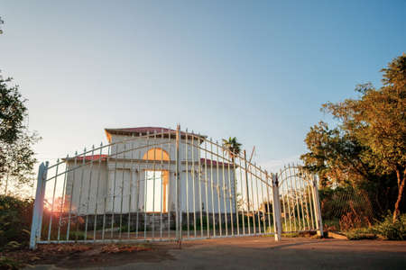 Abandoned building with closed rusty white metal gate and
