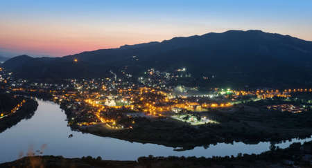 Aerial view of the ancient small illuminated town and view of the merger of two rivers at night