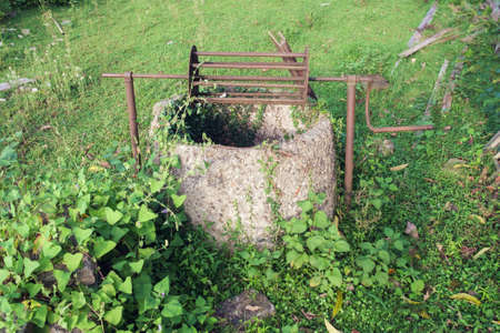An old abandoned well in a field overgrown with green ivyの写真素材