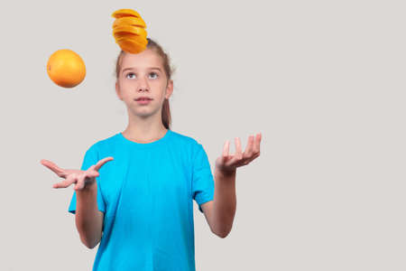 A girl in blue shirt juggling oranges