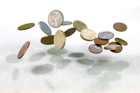 Different countries coins falling down on the white canvass surface. Coins levitating in the air