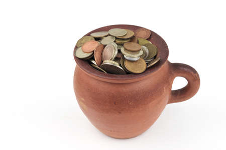 Clay brown pot full of various money coins, isolated on a white background