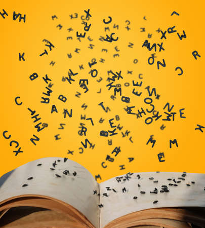 Letters of the alphabet in levitation in the air over the open book pagesの写真素材