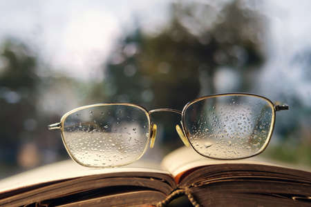 Glasses and open book on the window sill, selective focusの写真素材