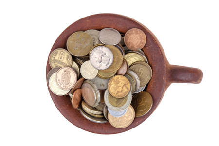Top view of a clay brown pot full of various money coins, isolated on a white background